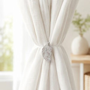 White leaf magnetic tieback holding back a light linen curtain by a bright window