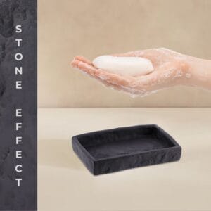 Hand holding bar soap above black stone effect soap dish