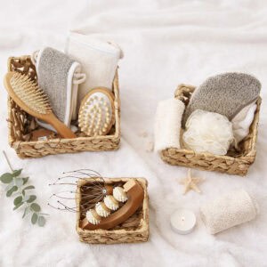 Three water hyacinth baskets filled with spa essentials including hairbrushes, massage tools, loofahs, and towels, styled with a candle and starfish.
