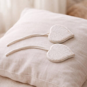 White carved wooden leaf tiebacks on linen cushion