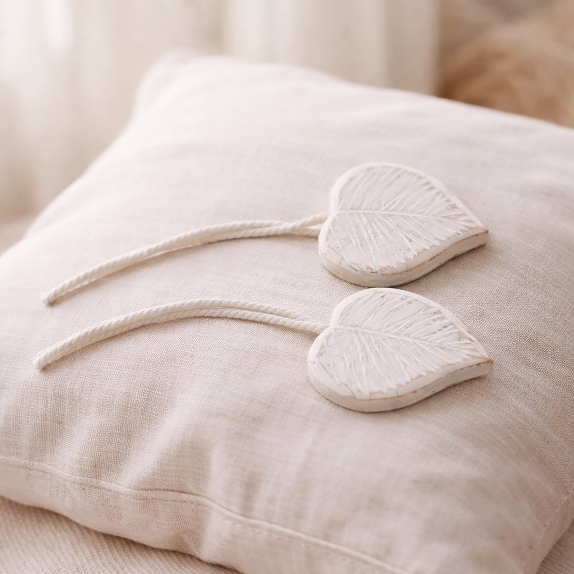 White carved wooden leaf tiebacks on linen cushion