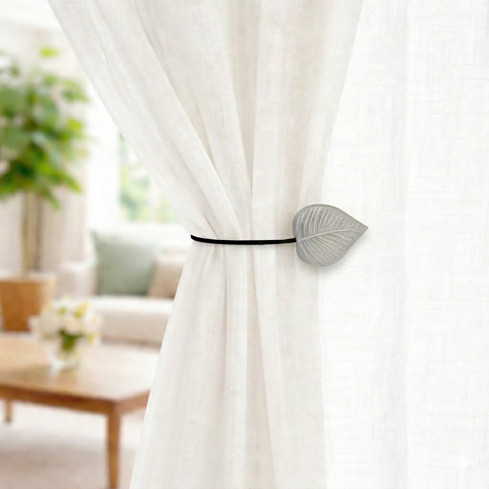 Gray leaf curtain tieback on sheer curtain, bright living room