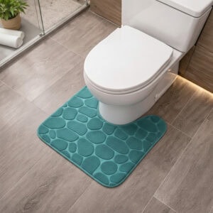 Peacock blue memory foam contour bath mat with pebble texture positioned around toilet base, angled view