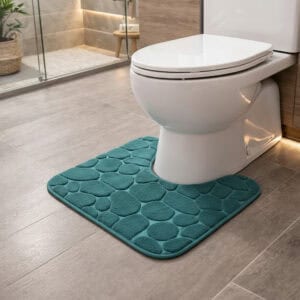 Peacock blue pebble-embossed memory foam contour mat around toilet, side-angle view in modern bathroom