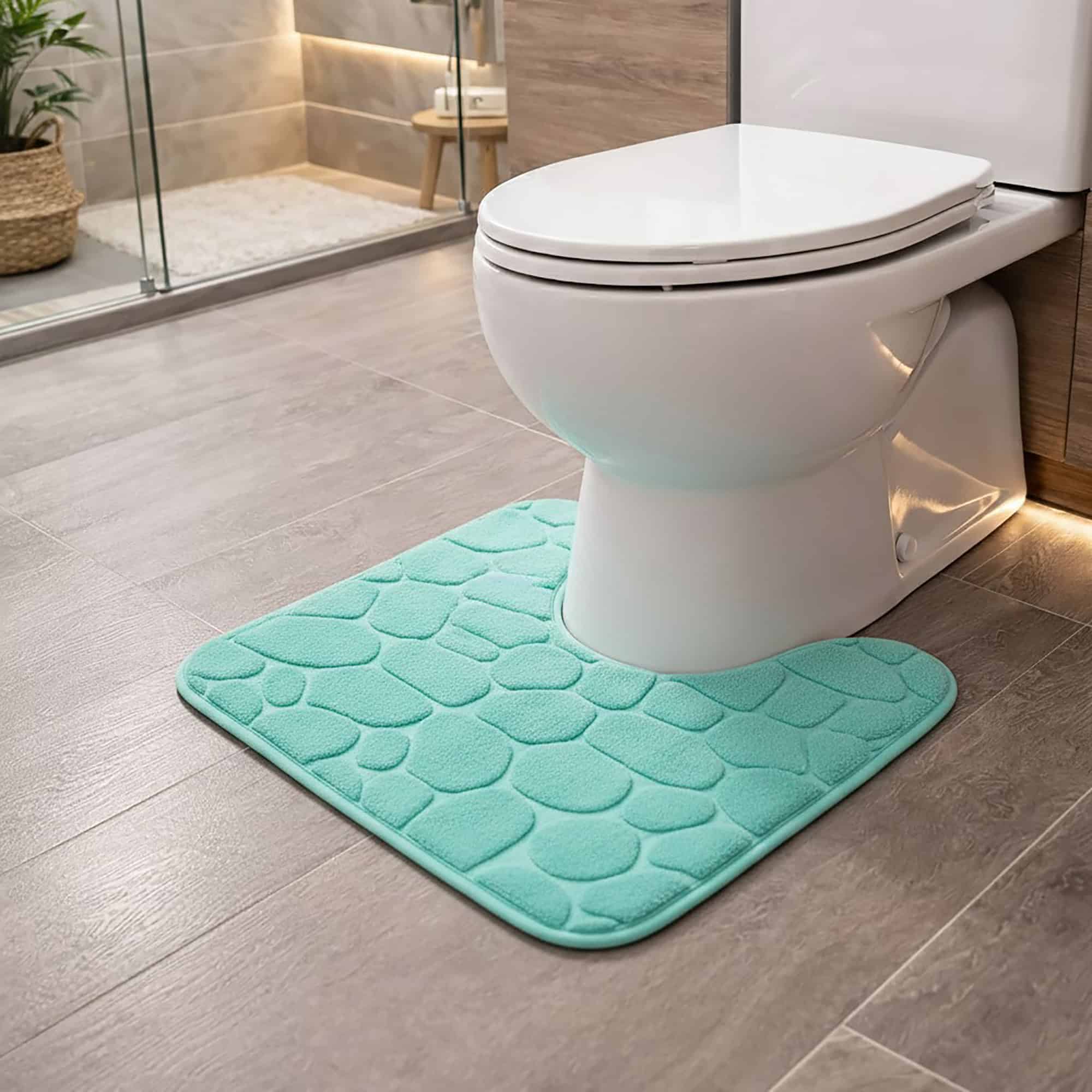 Aqua blue pebble-embossed memory foam contour mat around toilet, side-angle view in modern bathroom