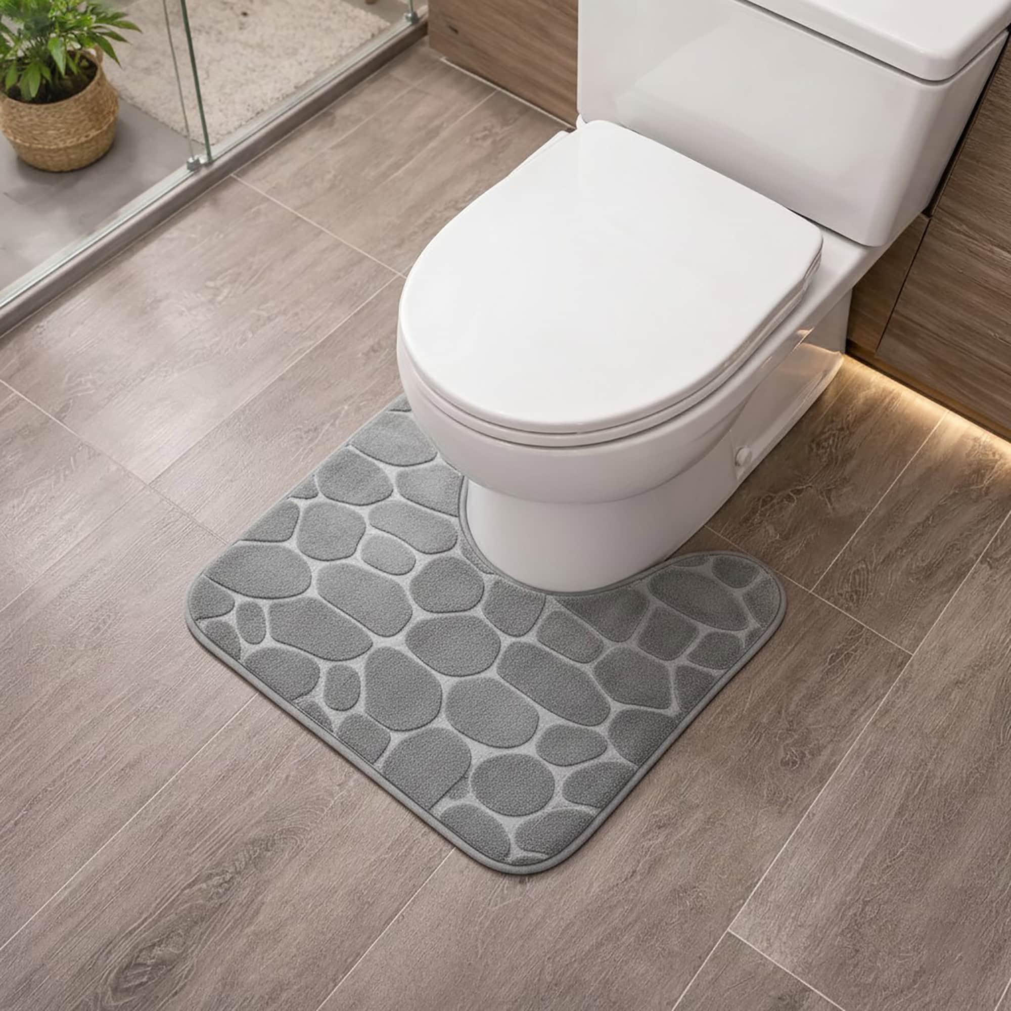 Light gray memory foam contour bath mat with pebble texture positioned around toilet base, angled view