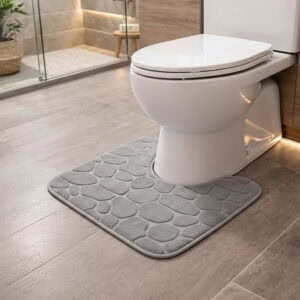 Light gray pebble-embossed memory foam contour mat around toilet, side-angle view in modern bathroom