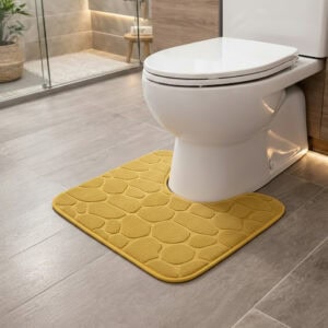 Mustard yellow pebble-embossed memory foam contour mat around toilet, side-angle view in modern bathroom