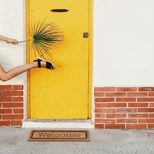 Welcome coir doormat in front of yellow door with person walking
