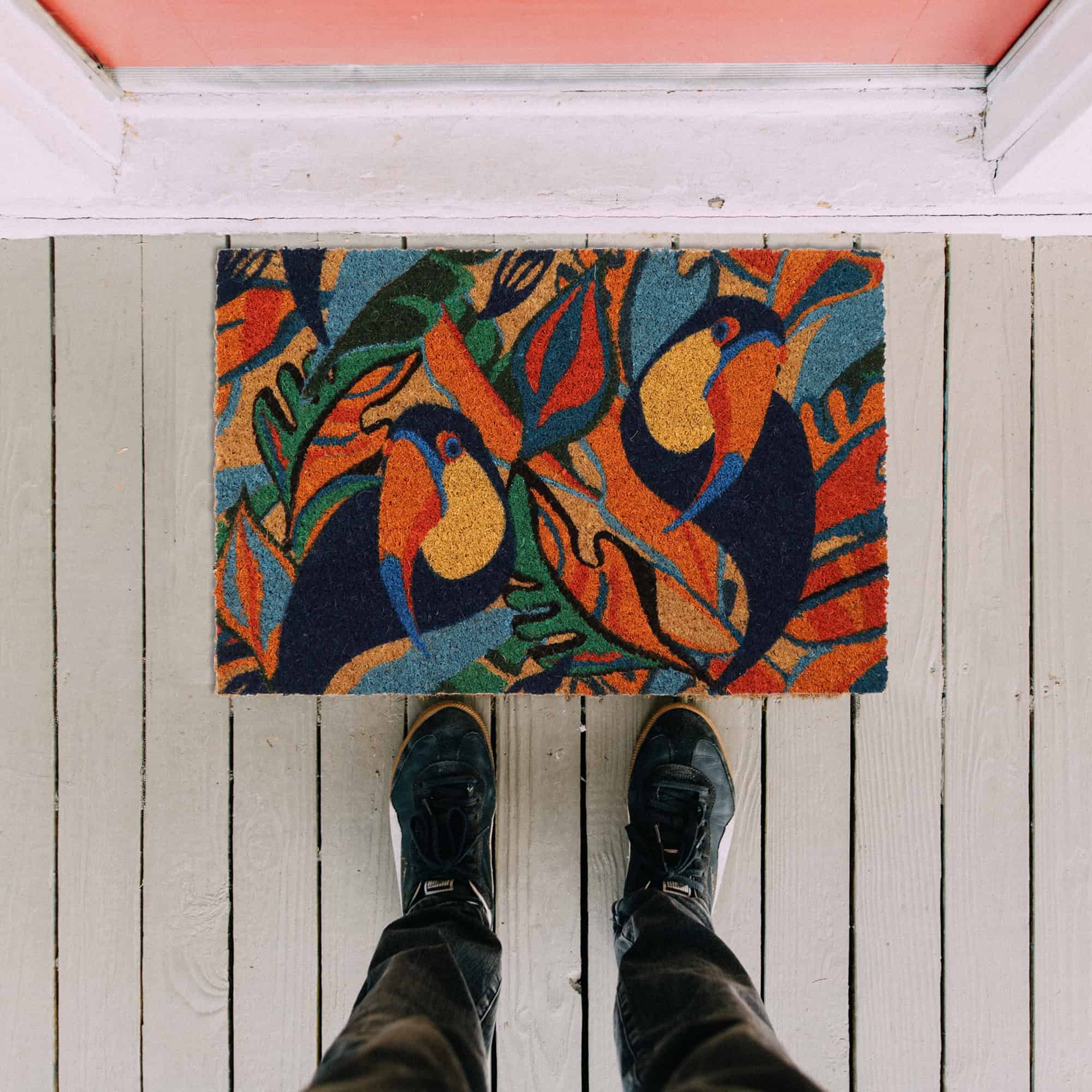 toucans door mat in situation on the floor with man legs and feet