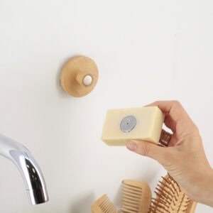 "Hand holding bar soap with embedded magnet near wall-mounted bamboo holder"