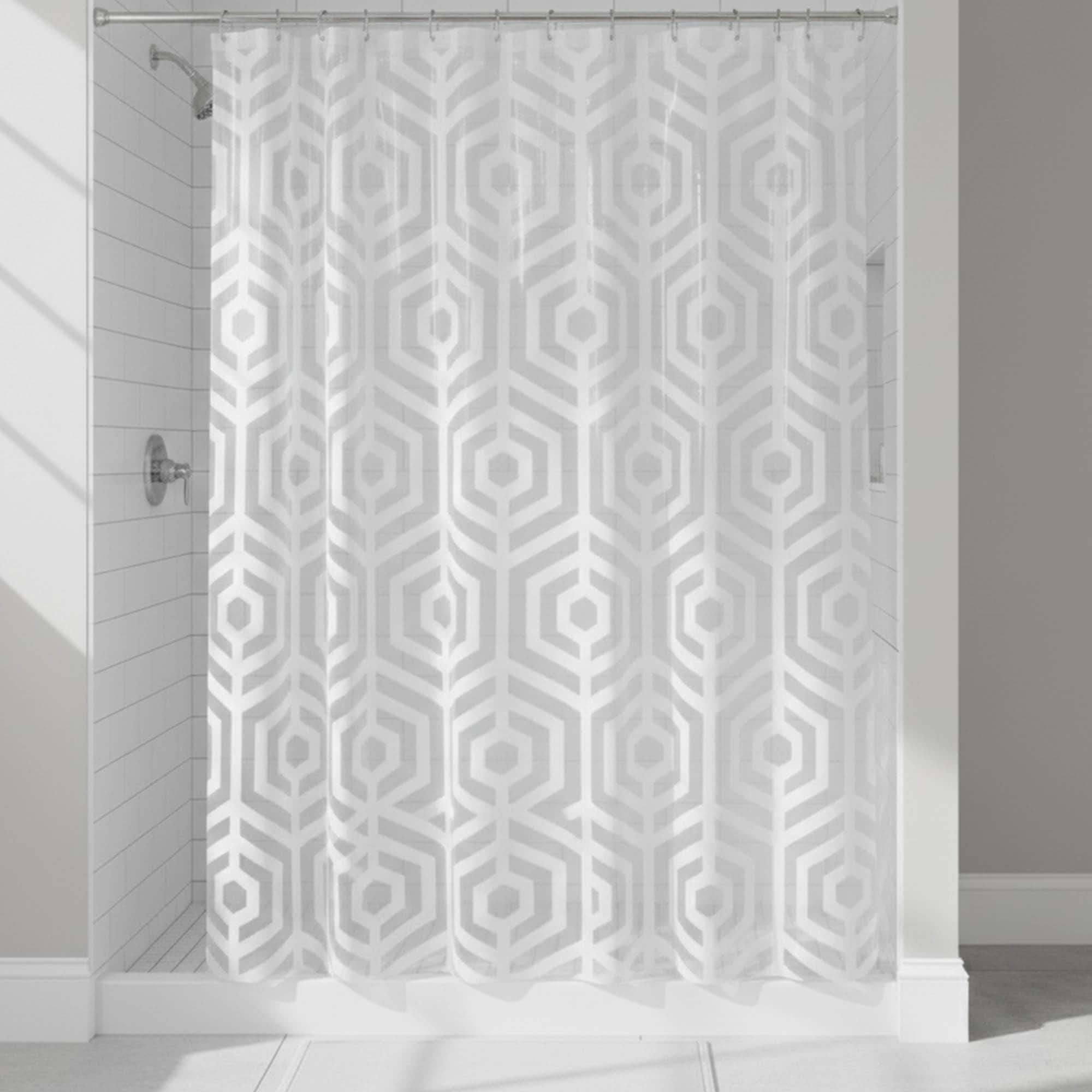 White hexagon-pattern shower curtain hanging in tiled shower
