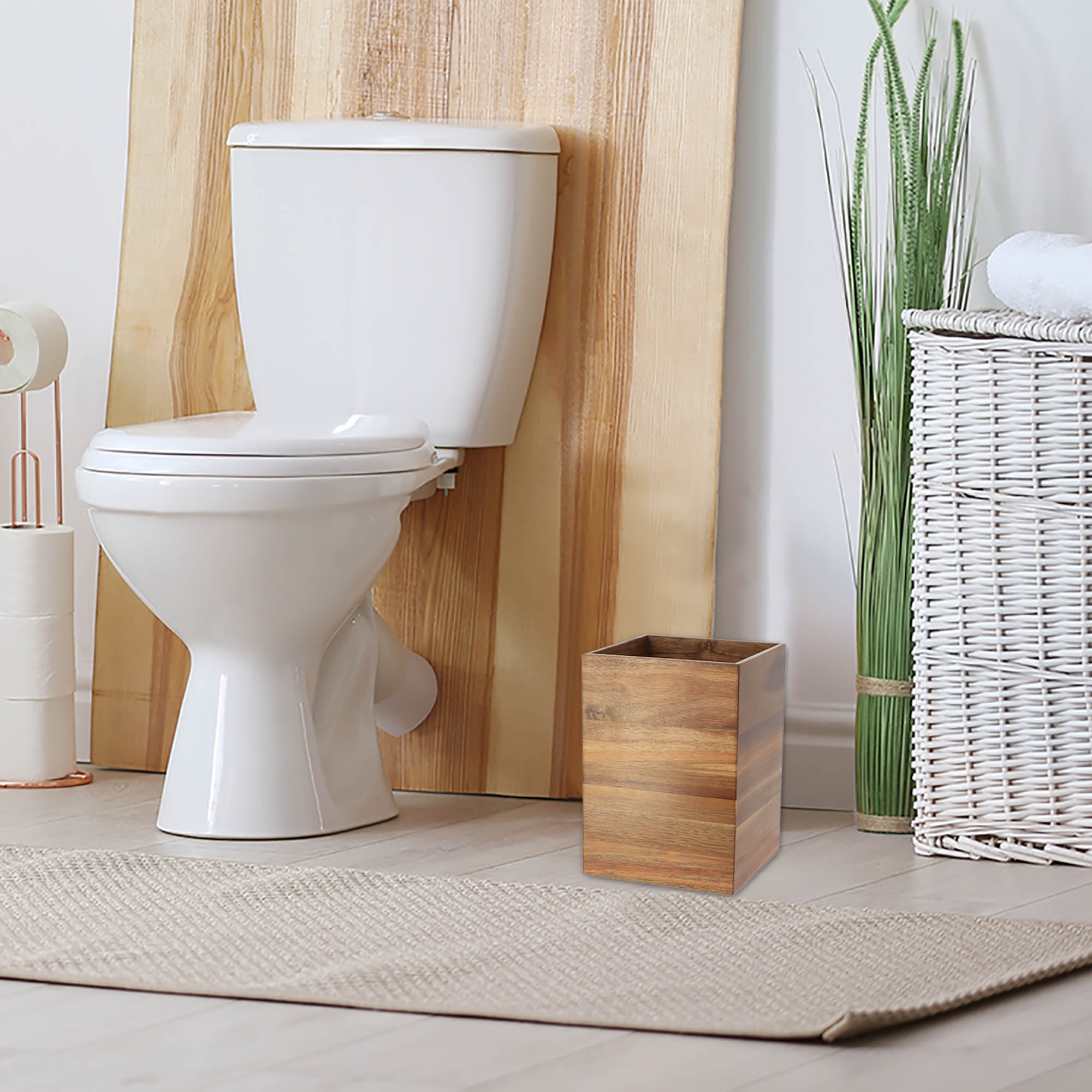 A wooden waste basket placed on the floor near a toilet in a bathroom.