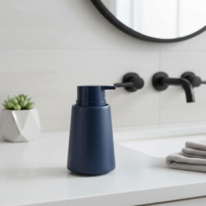Navy blue stoneware soap dispenser with pump on a modern bathroom sink countertop