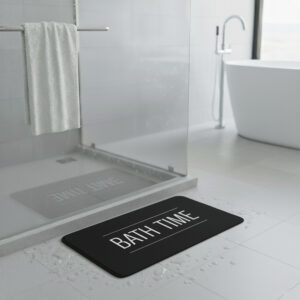 Black bath mat with white "BATH TIME" text on gray bathroom floor next to glass shower door