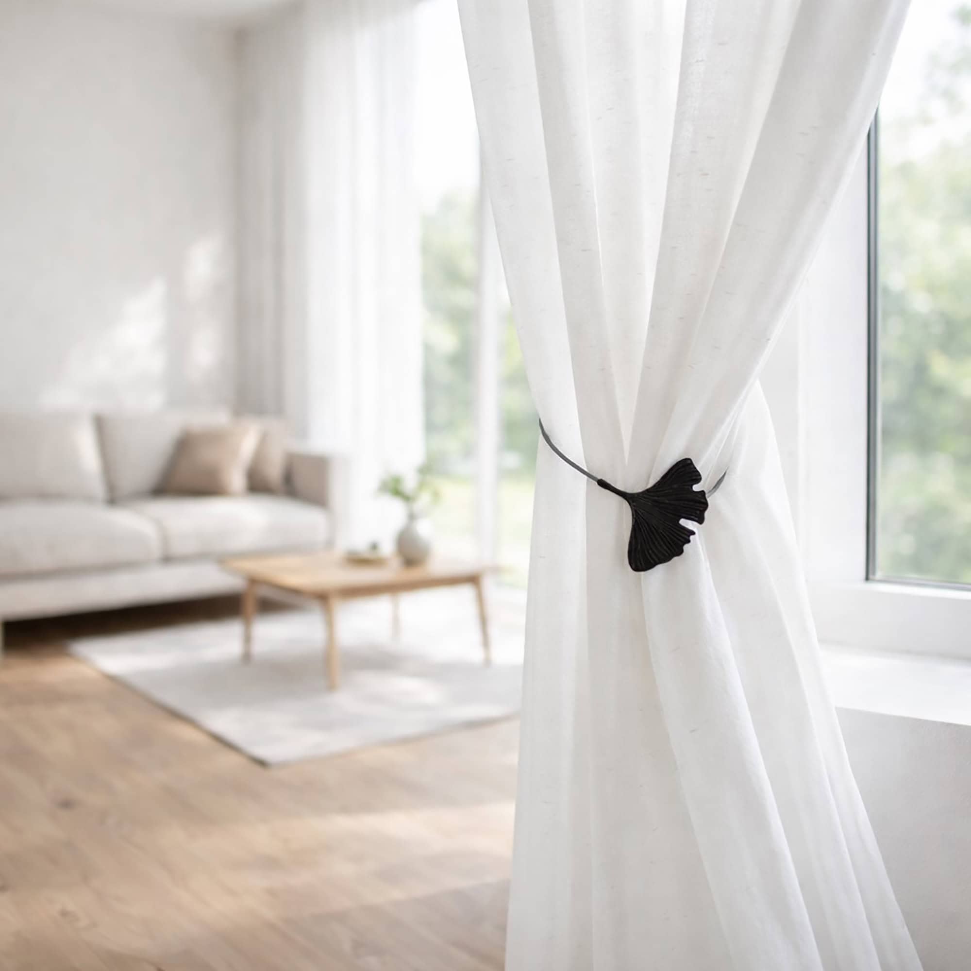 "Black ginkgo leaf magnetic curtain tieback holding white sheer curtains in a modern living room"