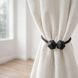 Black geometric curtain tieback holding bundled ivory linen curtain