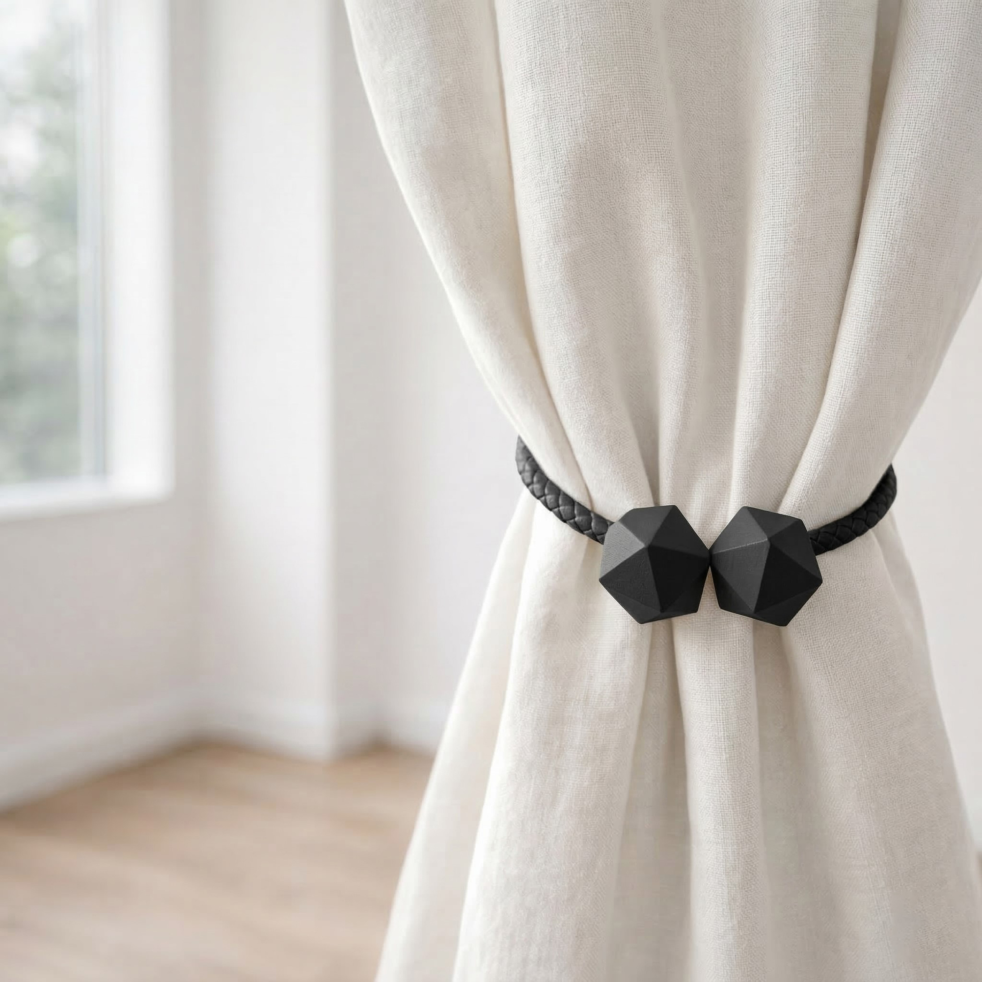 Black geometric curtain tieback holding bundled ivory linen curtain