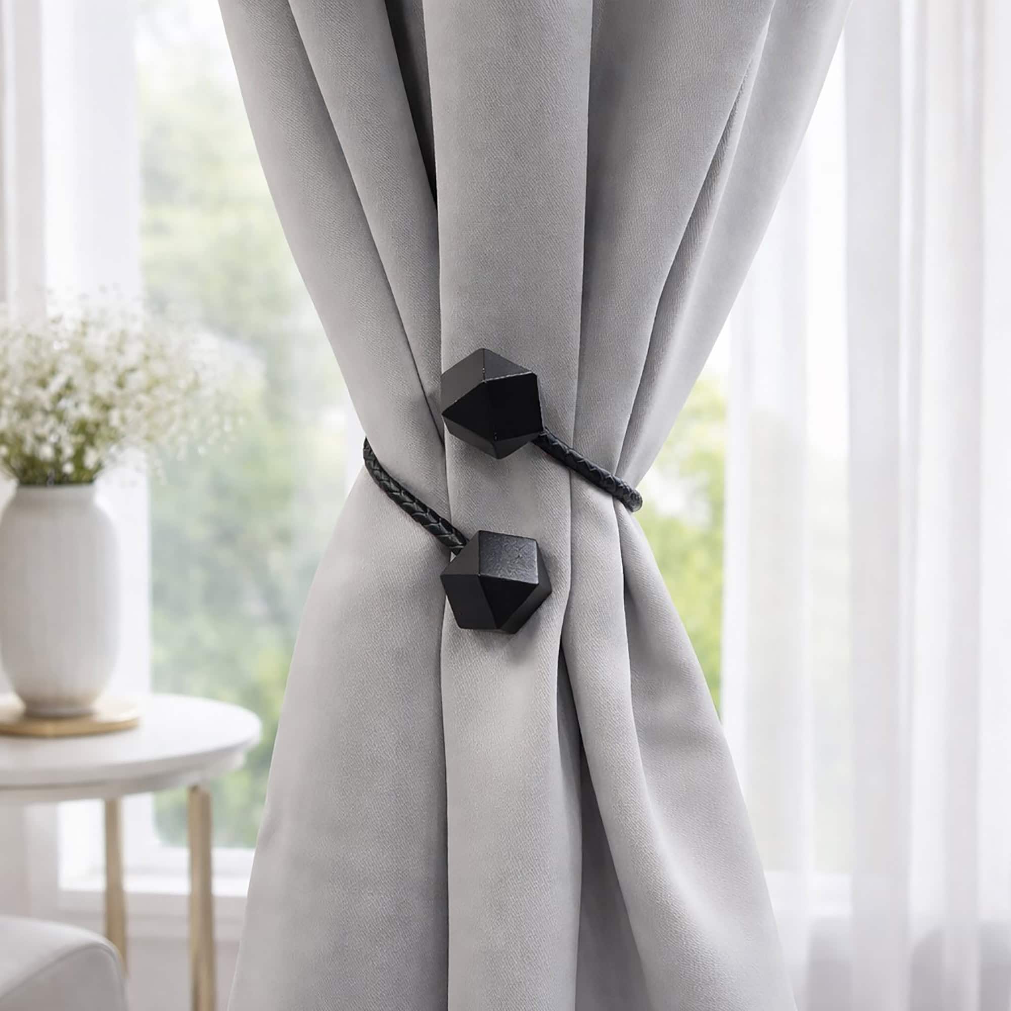 Black geometric tieback fastened around grey curtain, bright living room setting