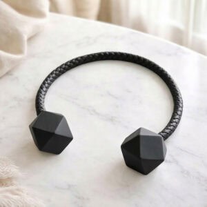 Black braided curtain tieback with faceted wooden ends on marble surface