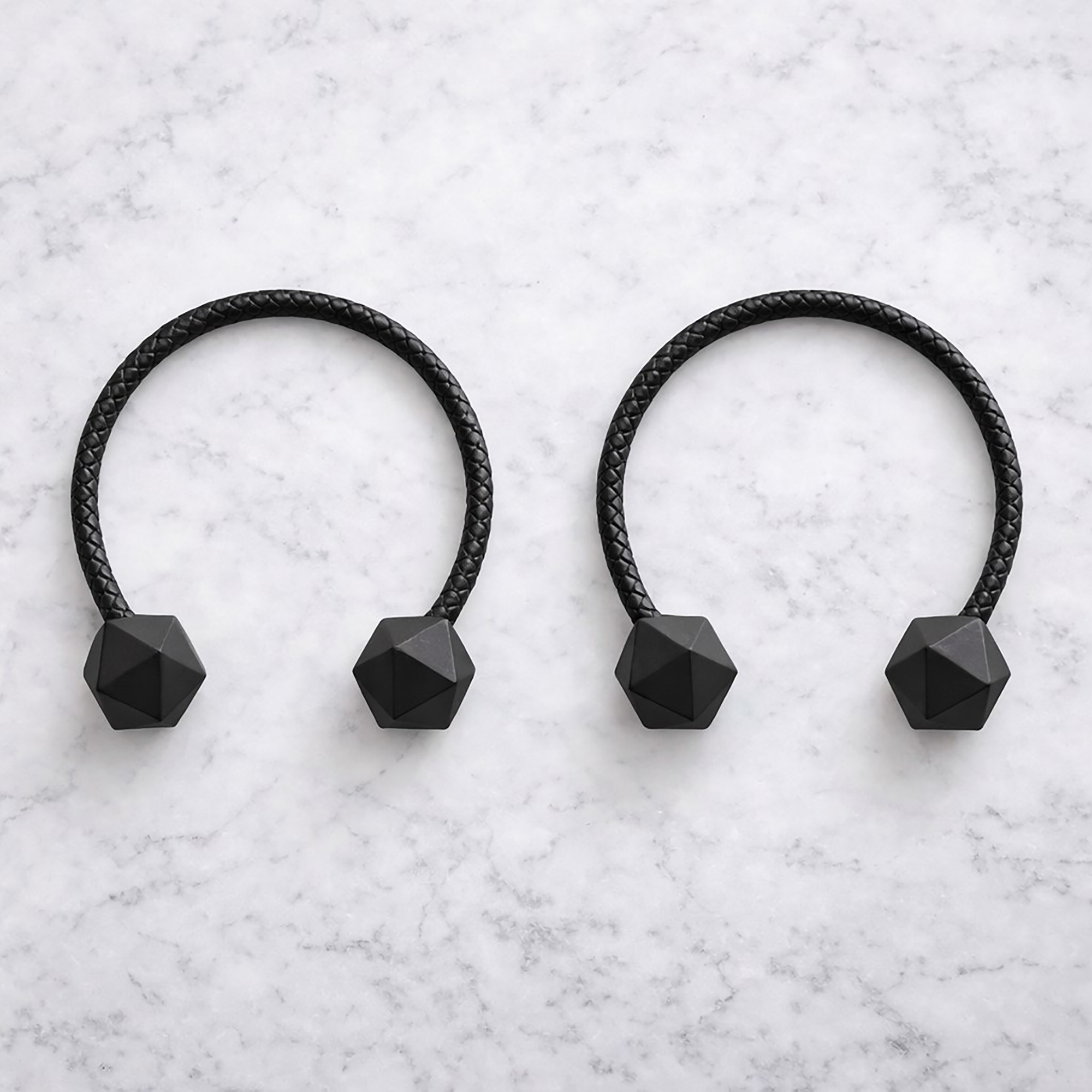Black braided curtain tiebacks with faceted wooden ends on marble surface
