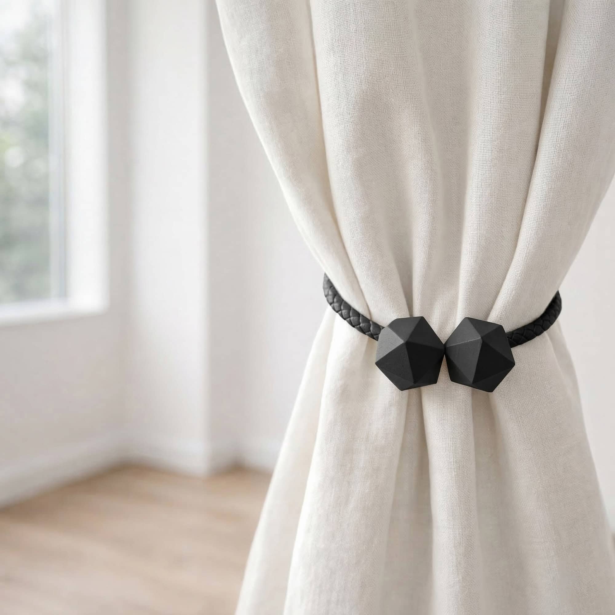 Black geometric curtain tieback holding bundled ivory linen curtain