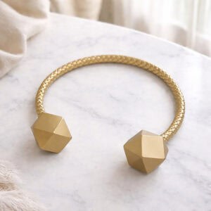 Gold braided curtain tieback with faceted wooden ends on marble surface