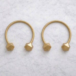 Gold braided curtain tiebacks with faceted wooden ends on marble surface