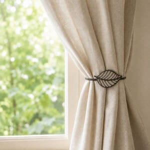Taupe leaf tieback holding a linen curtain back beside a sunny window