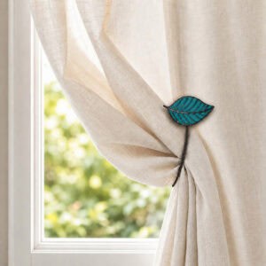Teal leaf tieback gathering a cream curtain in warm daylight