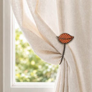 Terracotta leaf tieback gathering a cream curtain in warm daylight