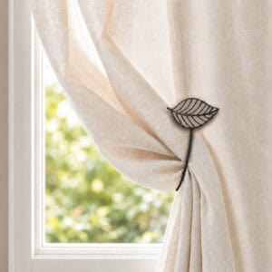 Taupe leaf tieback gathering a cream curtain in warm daylight