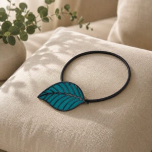 Teal leaf tieback resting on a linen cushion with eucalyptus accent