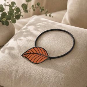 Terracotta leaf tieback resting on a linen cushion with eucalyptus accent