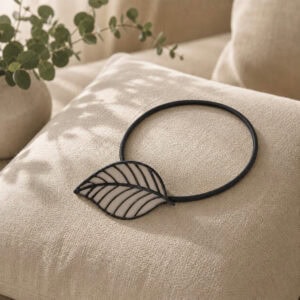 Taupe leaf tieback resting on a linen cushion with eucalyptus accent