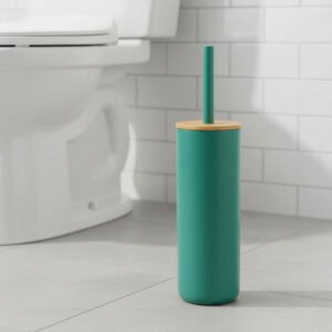 Teal green toilet brush with bamboo lid beside white toilet in bathroom with subway tile
