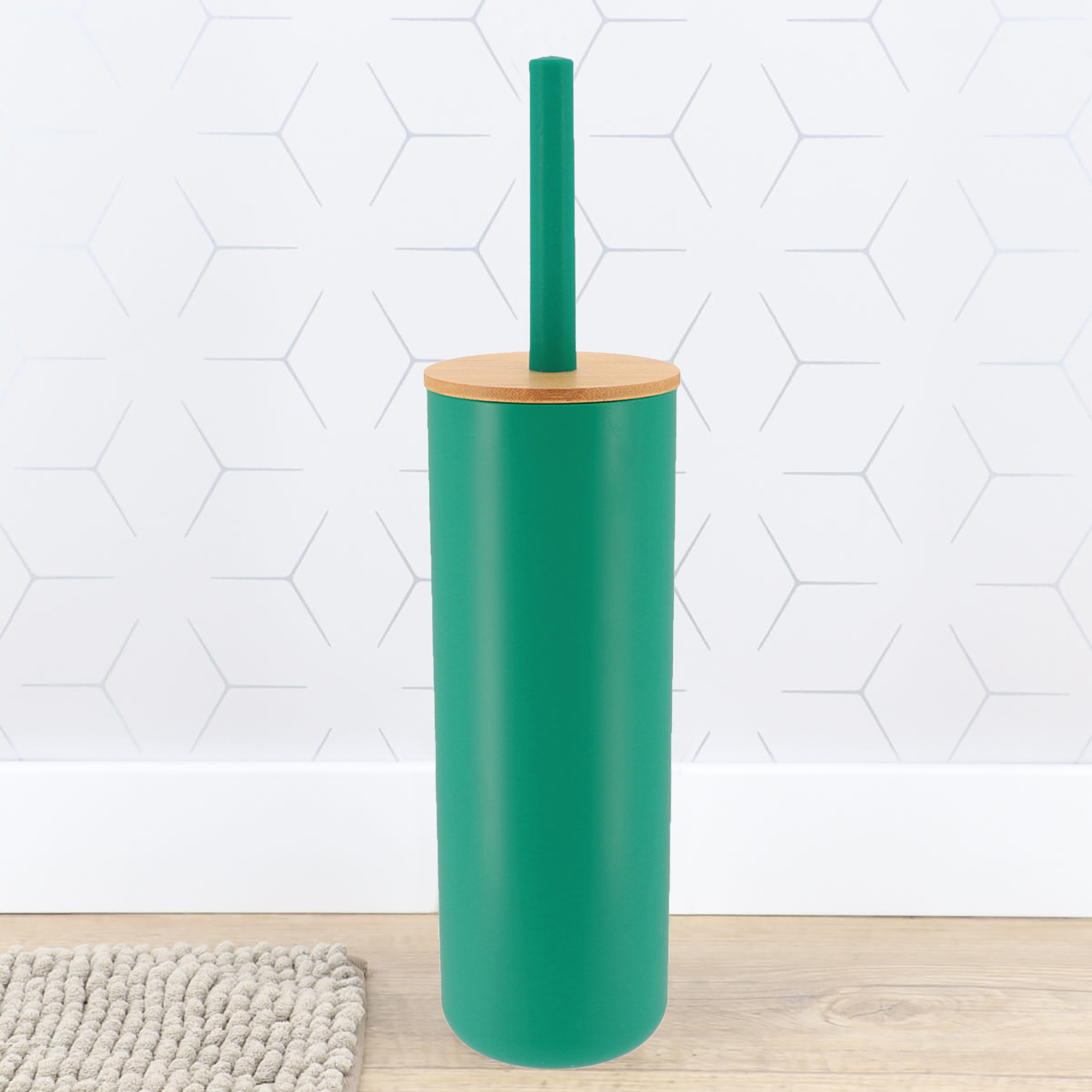Teal green toilet brush holder with bamboo lid against white hexagonal tile wall