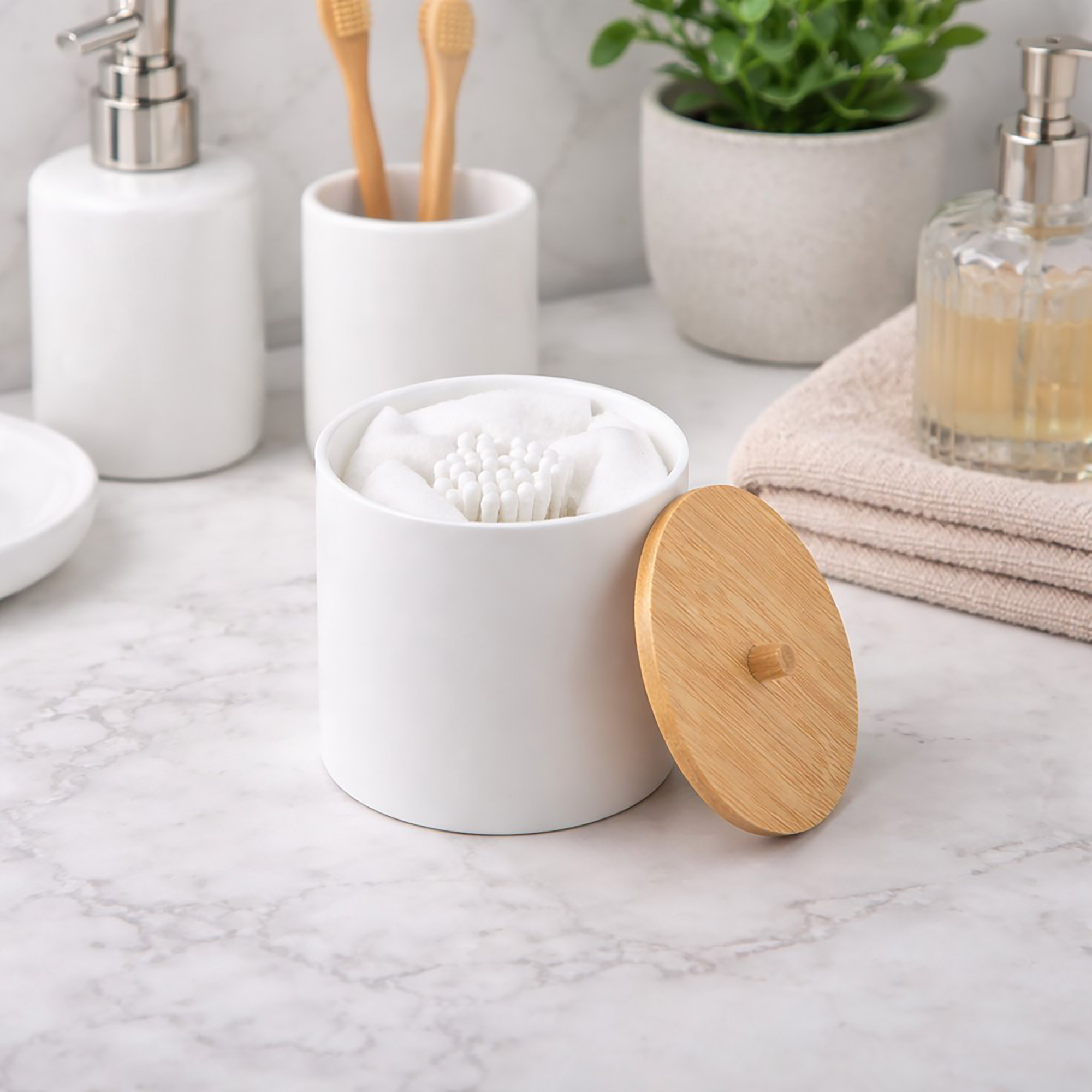 White cotton pad and Q-tip holder with bamboo lid on bathroom counter