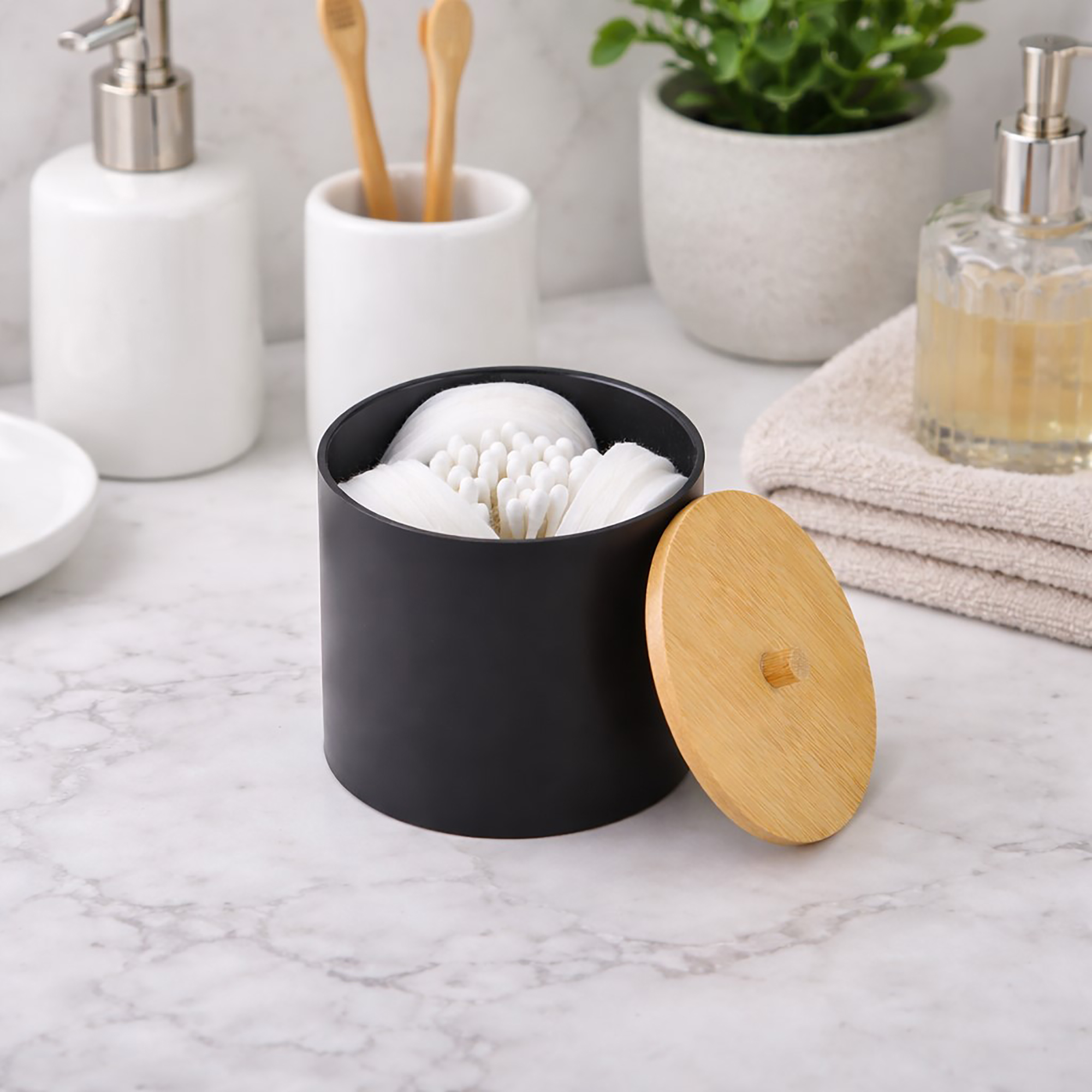 Black cotton pad and Q-tip holder with bamboo lid on bathroom counter