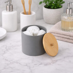 Gray cotton pad and Q-tip holder with bamboo lid on bathroom counter