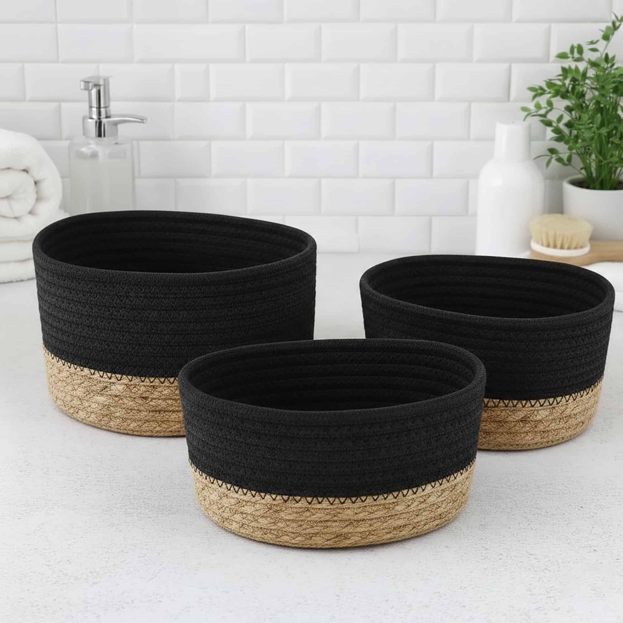 Three black cotton and seagrass oval baskets in graduated sizes displayed empty on a bathroom countertop.