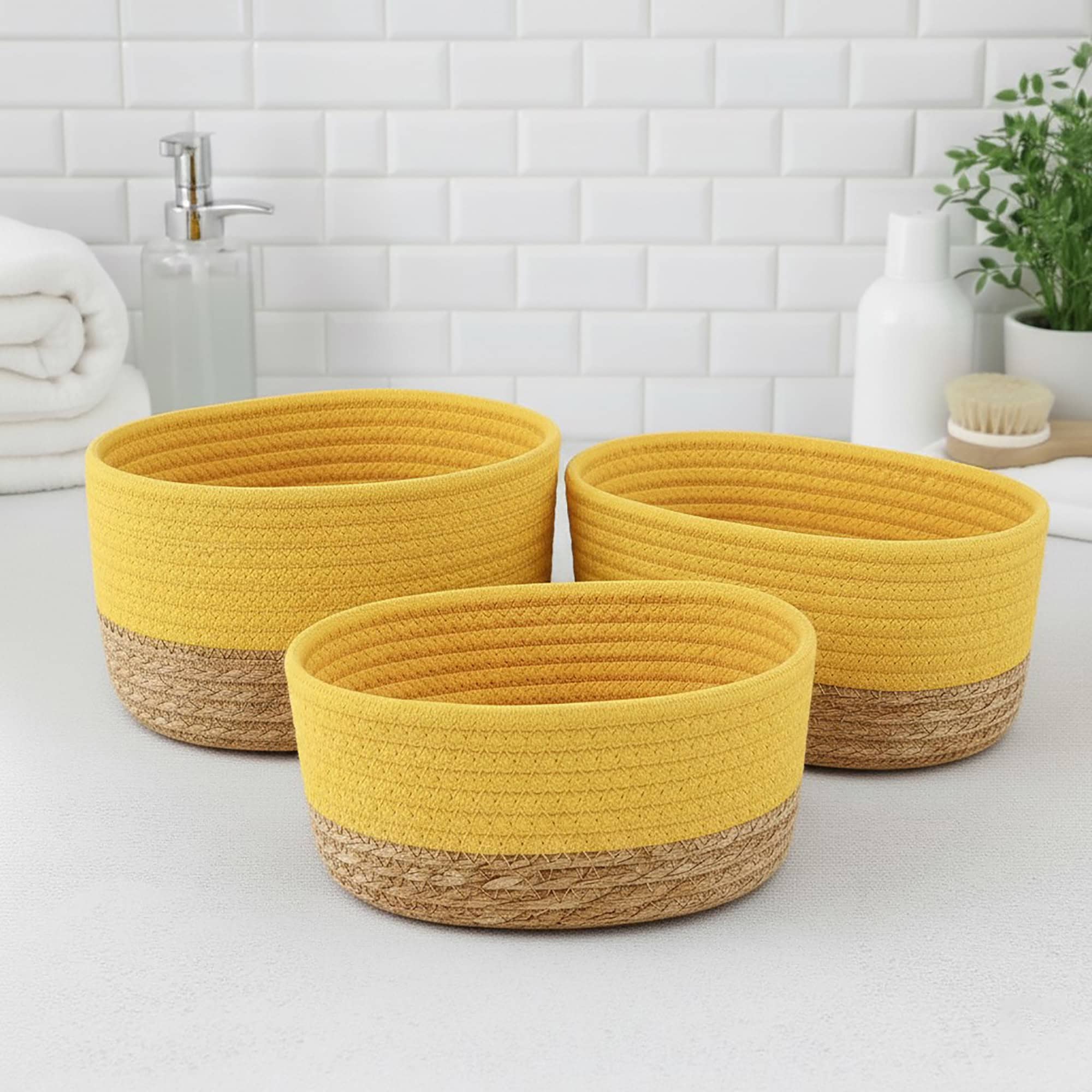 Three yellow cotton and seagrass oval baskets in graduated sizes displayed empty on a bathroom countertop.