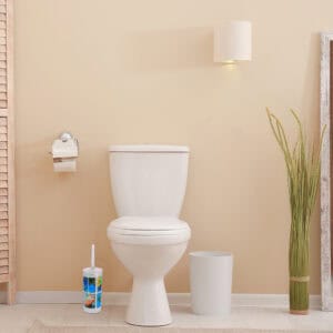 "Tropical print toilet brush holder beside white toilet in beige bathroom"