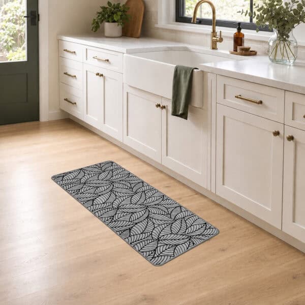 Grey leaf-print kitchen runner placed along white cabinets in front of a farmhouse sink in a bright, airy kitchen.