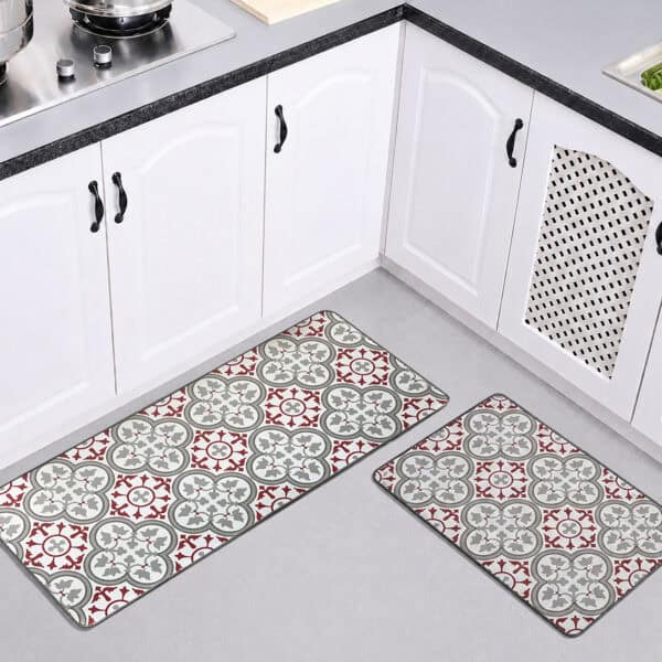 Both kitchen mats laid on the floor of a bright white kitchen, the longer runner and the smaller mat showing their red and gray tile pattern.