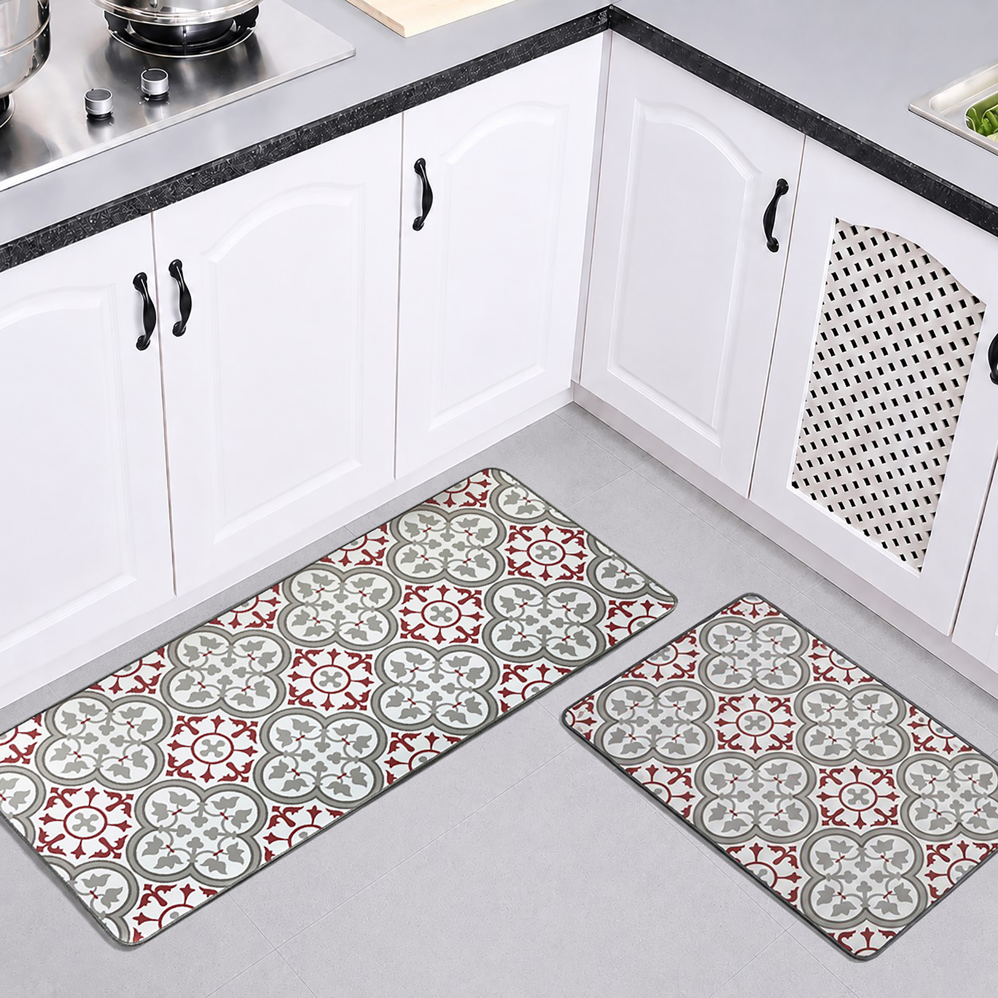 Both kitchen mats laid on the floor of a bright white kitchen, the longer runner and the smaller mat showing their red and gray tile pattern.