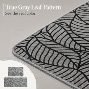 Close-up of a grey kitchen mat showing the true leaf-pattern color, the woven texture and the soft stitched grey border.