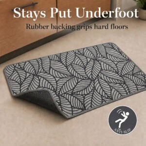 Grey kitchen mat lifted at one corner to reveal the textured rubber backing that grips hard floors and prevents slipping underfoot.