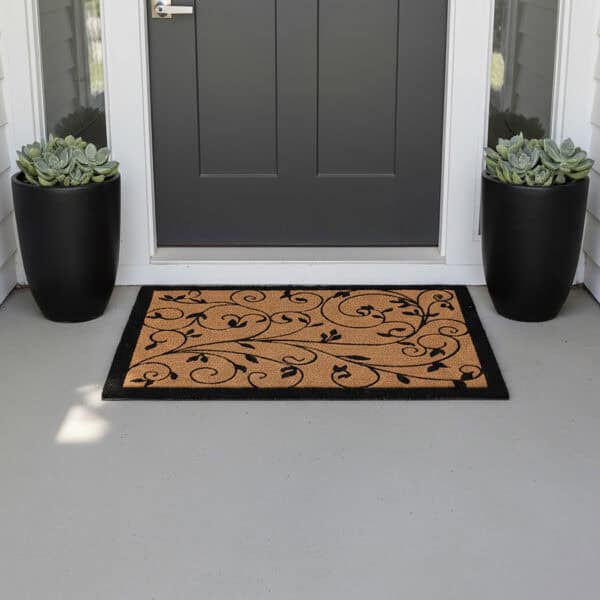 Leafy vine natural coir doormat at dark entry door with black planters