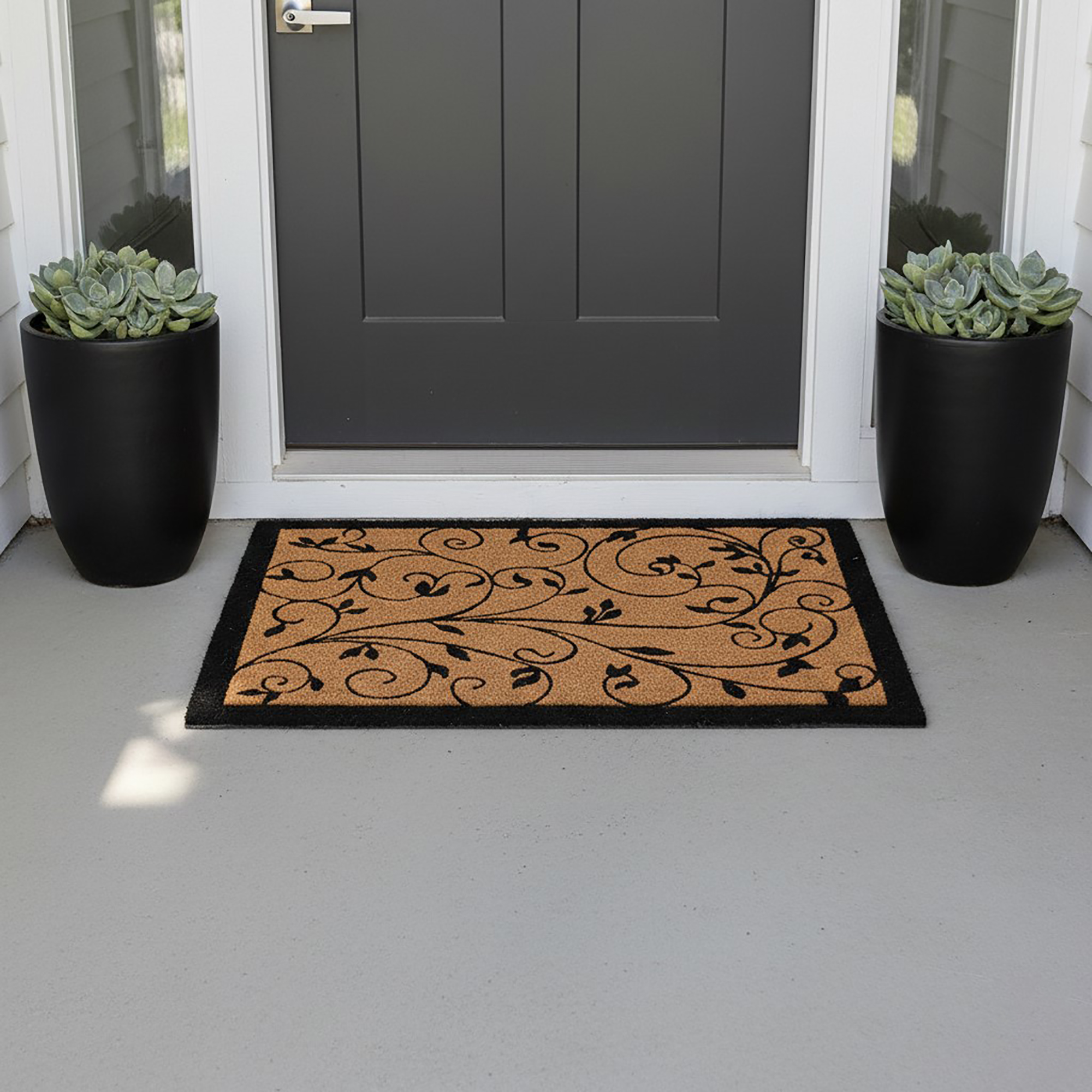 Leafy vine natural coir doormat at dark entry door with black planters